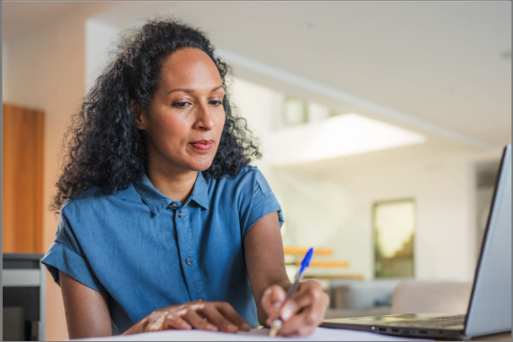 woman writing with laptop open